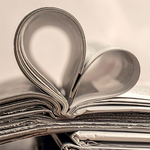This image is an artistic composition featuring an open book with its pages meticulously folded to form a heart shape, often representing a love for reading, literature, or romance.